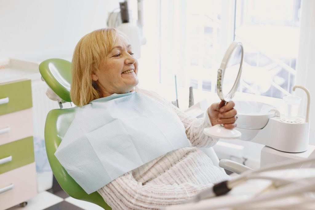 Senior woman smiling in dental chair after dental implant treatment